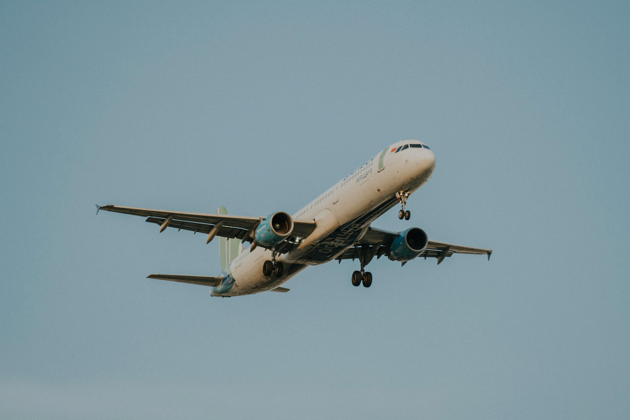 Low angle shot of a passenger airplane with blue sky backdrop, showcasing aviation technology in flight.